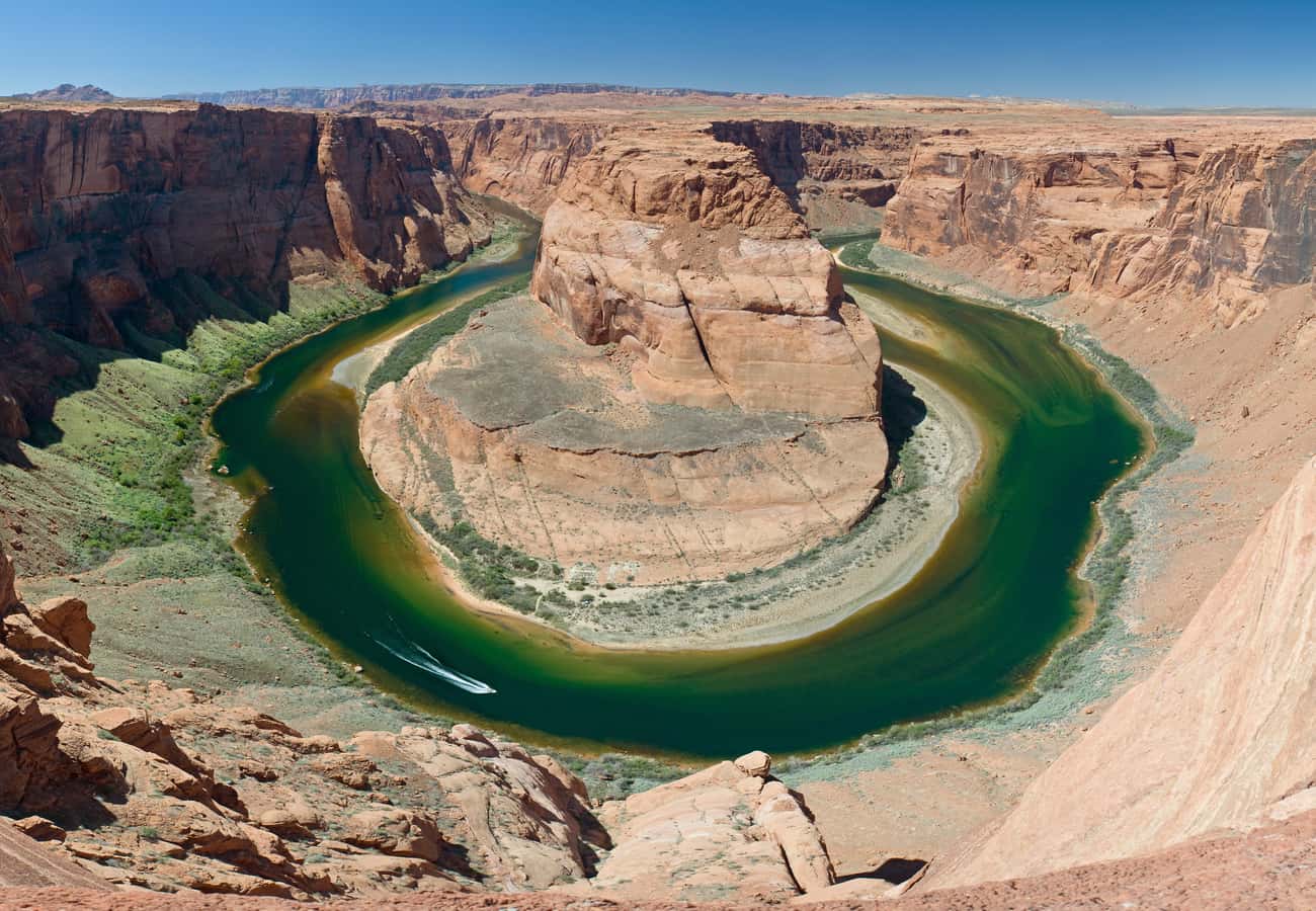 Aerial view of the Colorado River curving dramatically around a massive sandstone rock formation at Horseshoe Bend in Page Arizona