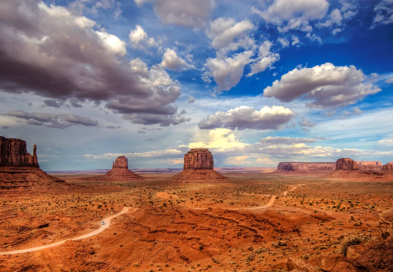 Vast landscape of towering red sandstone buttes and mittens rising from the desert floor along Valley Drive in Monument Valley