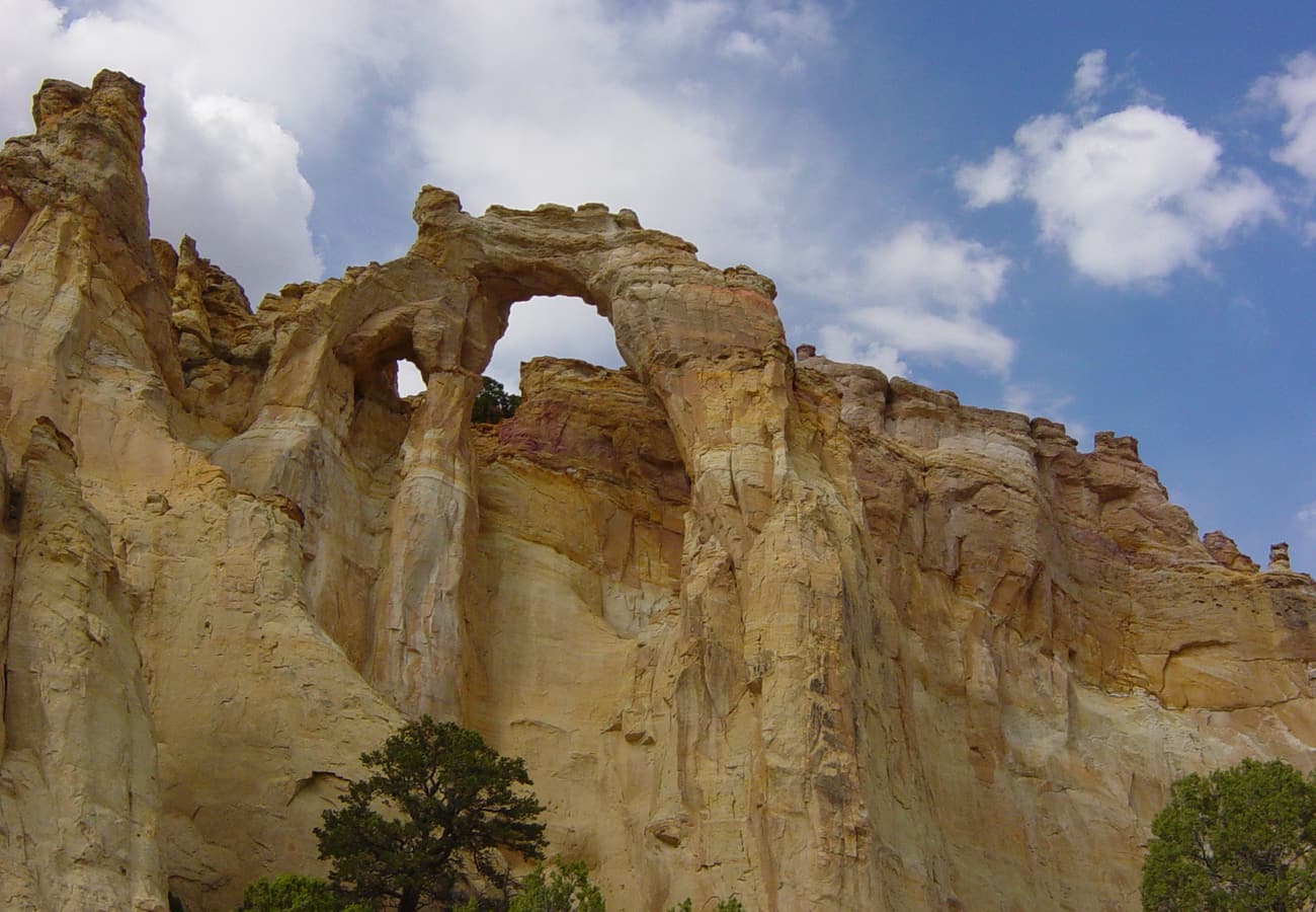 Monumental yellow sandstone double arch of Grosvenor Arch rising above the desert hills in Grand Staircase-Escalante