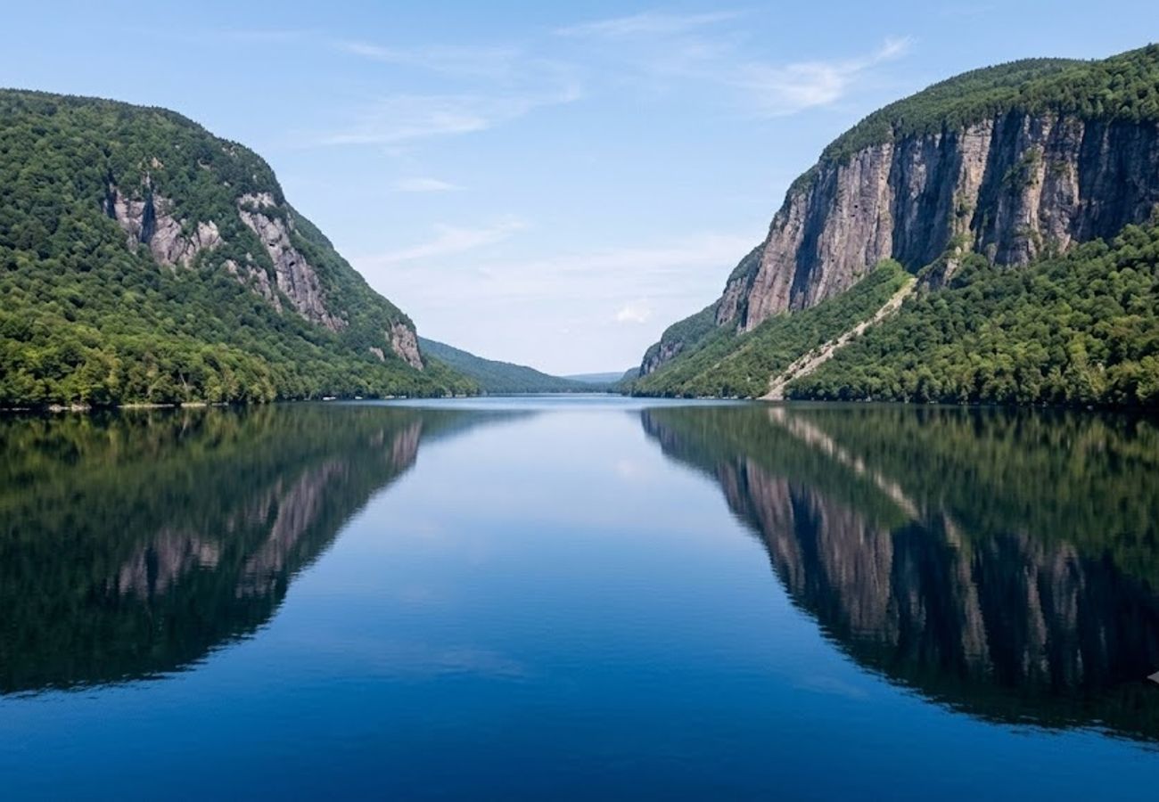Deep blue glacial lake surrounded by sheer green and autumn mountain cliffs reflecting across mirror-still water in Vermont