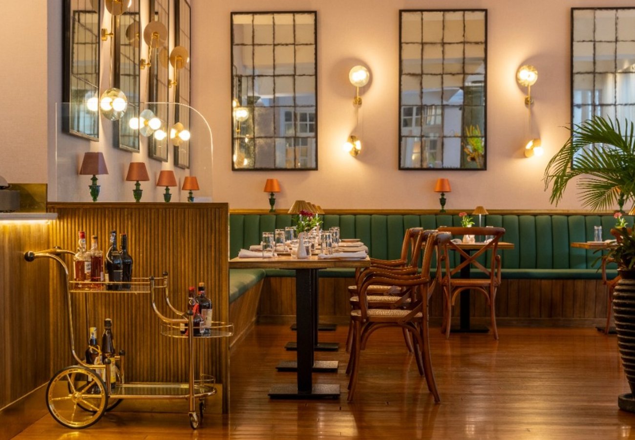 The elegant Hemingways Brasserie dining room with bespoke bar cart and warm brass accents
