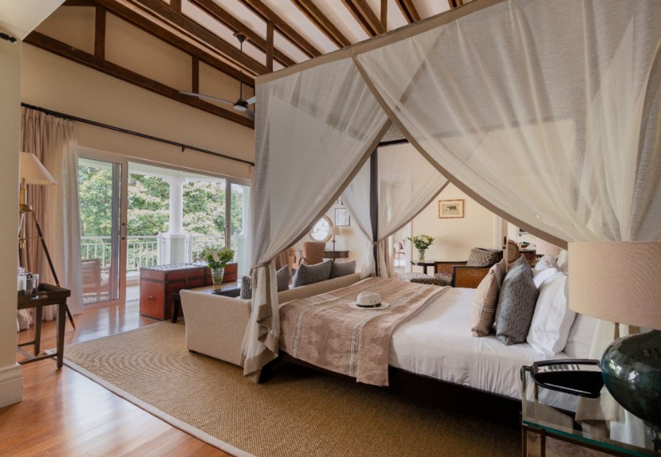 Luxury plantation-style suite featuring four-poster canopy bed and private terrace overlooking the gardens