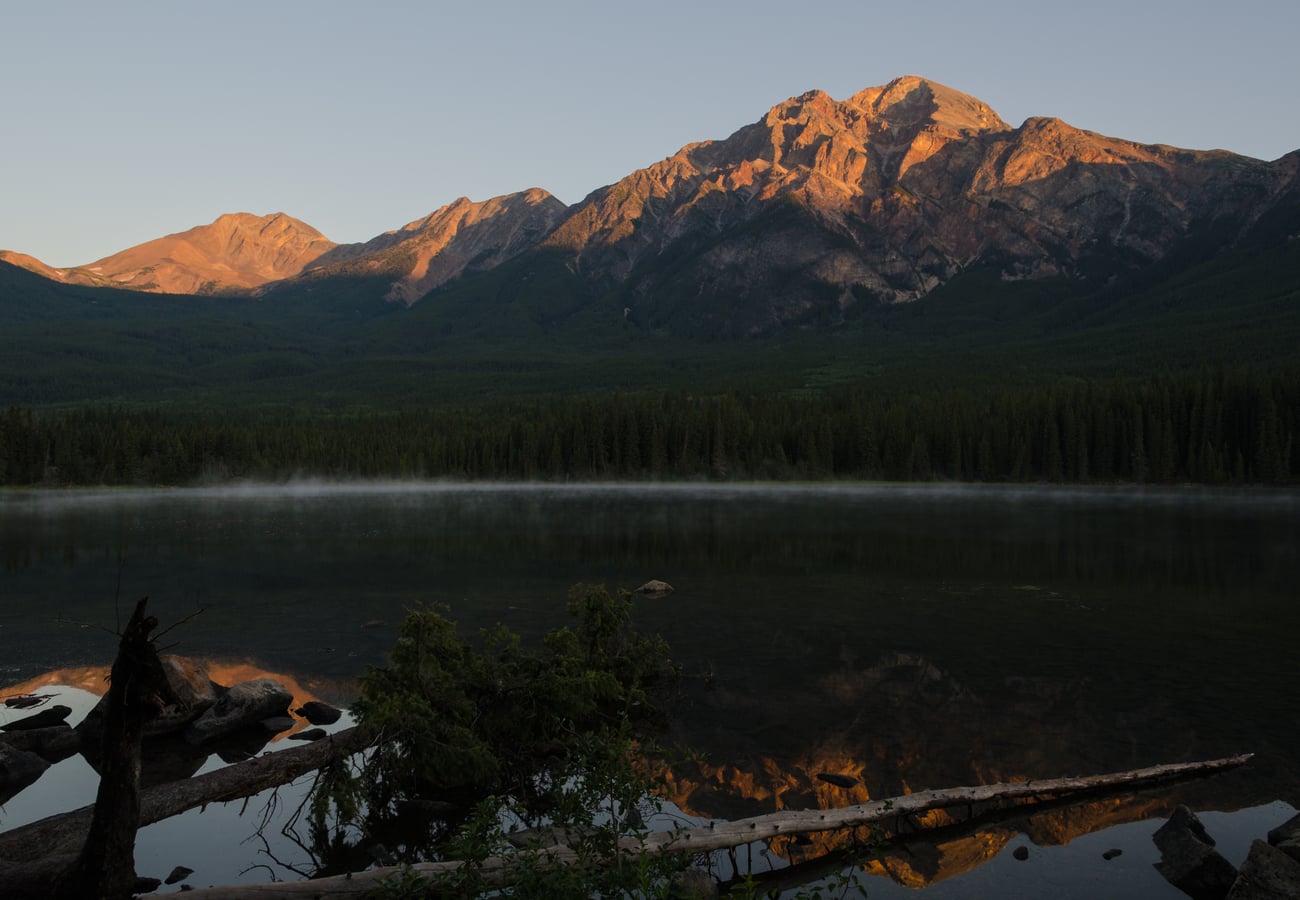 Dawn reflections of Pyramid Mountain reddish sandstone summit across the glass-still waters of Pyramid Lake