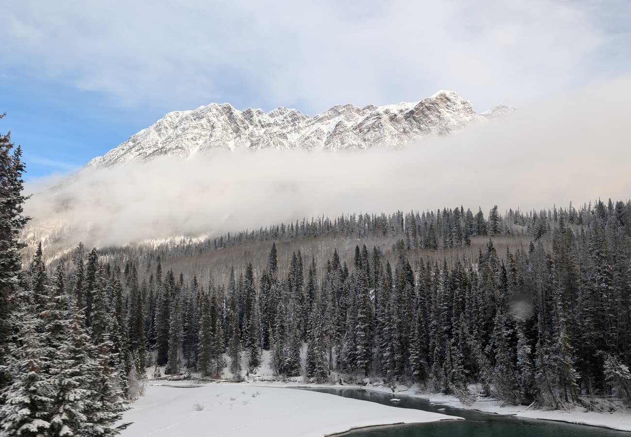 Canadian Rockies mountain highway stretching toward towering granite peaks between Alberta and British Columbia