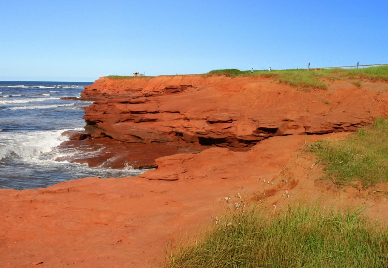 Rust-red sandstone sea cliffs and sand dunes at Cavendish Beach
