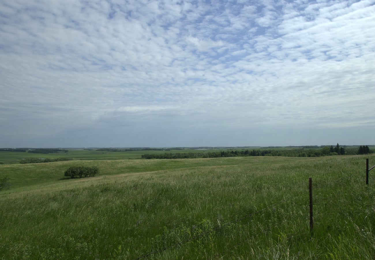 Expansive rolling prairies and farmland under wide open skies