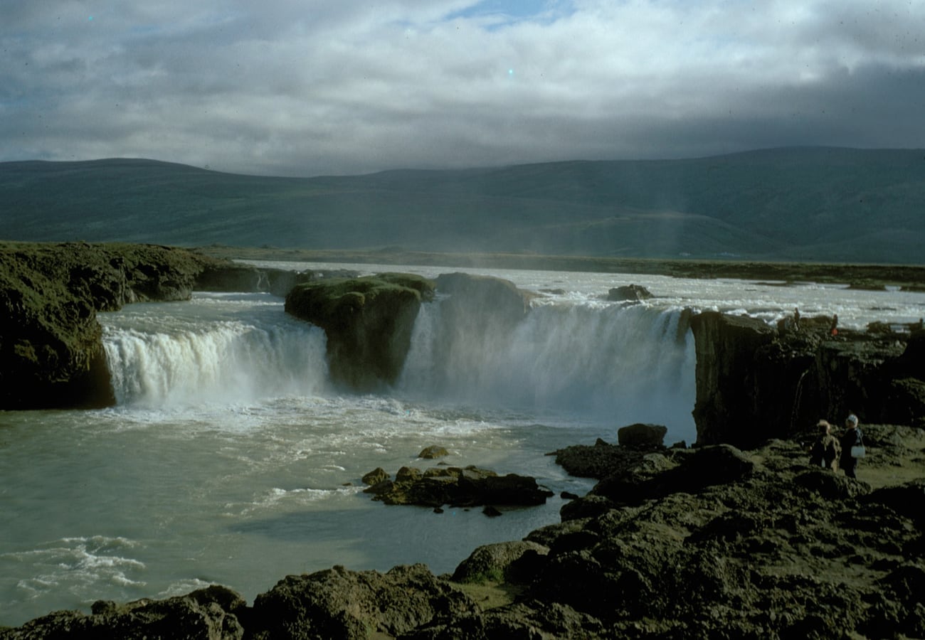 The semicircular amphitheater of Goðafoss waterfall plunging into churning waters