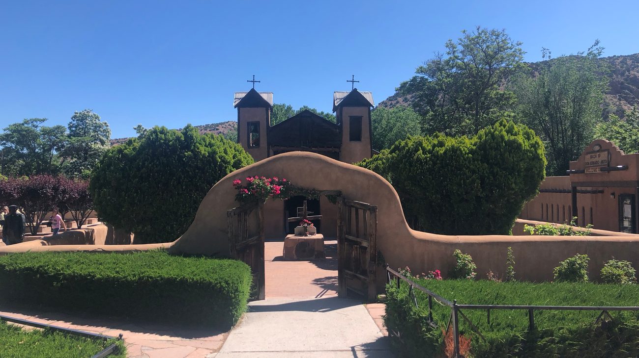 Historic adobe facade and twin bell towers of El Santuario de Chimayo along the High Road to Taos