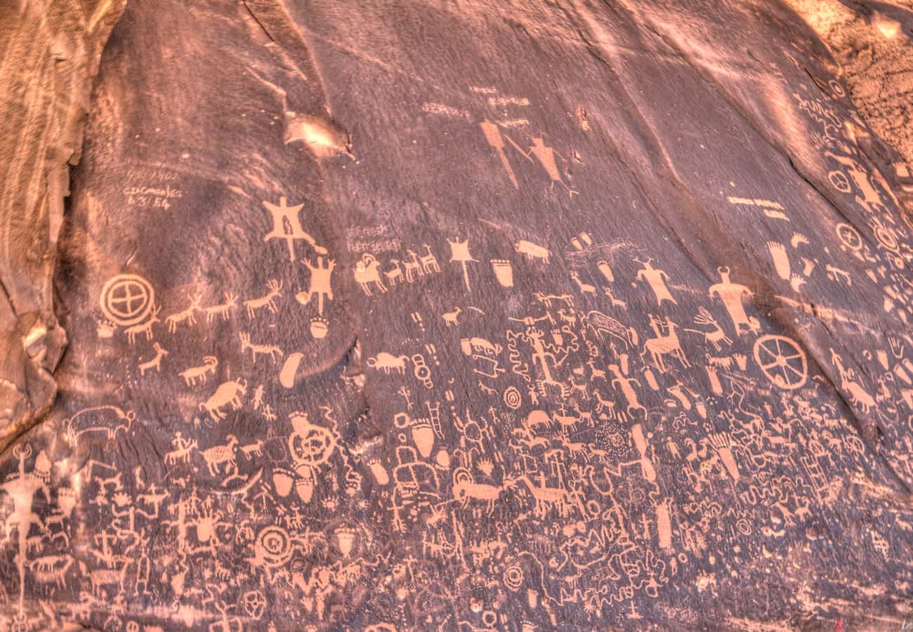 Historic Native American petroglyphs covering the dark desert varnish of Newspaper Rock in Utah