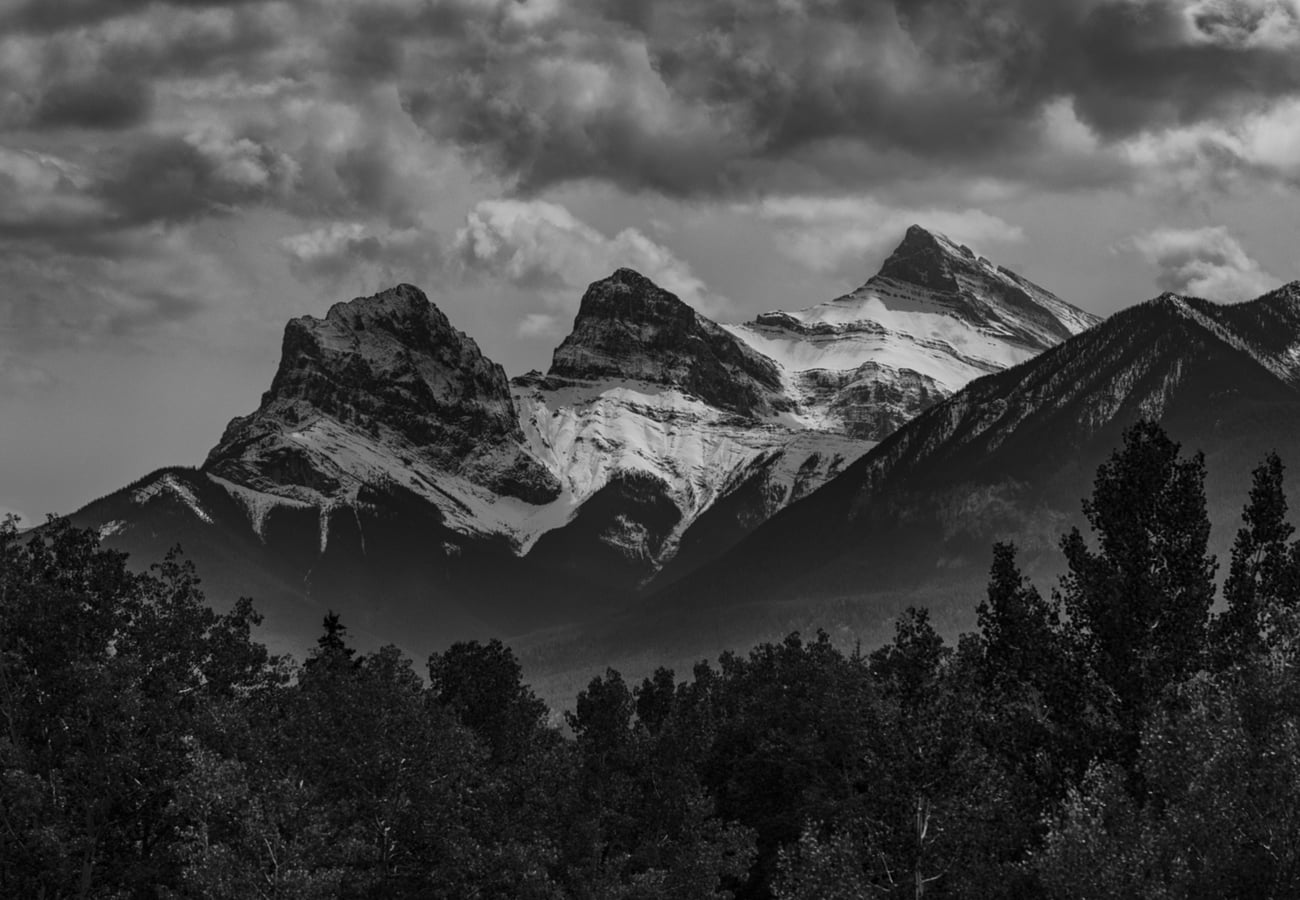 The iconic jagged three-peak skyline of the Three Sisters mountains towering over Canmore Alberta