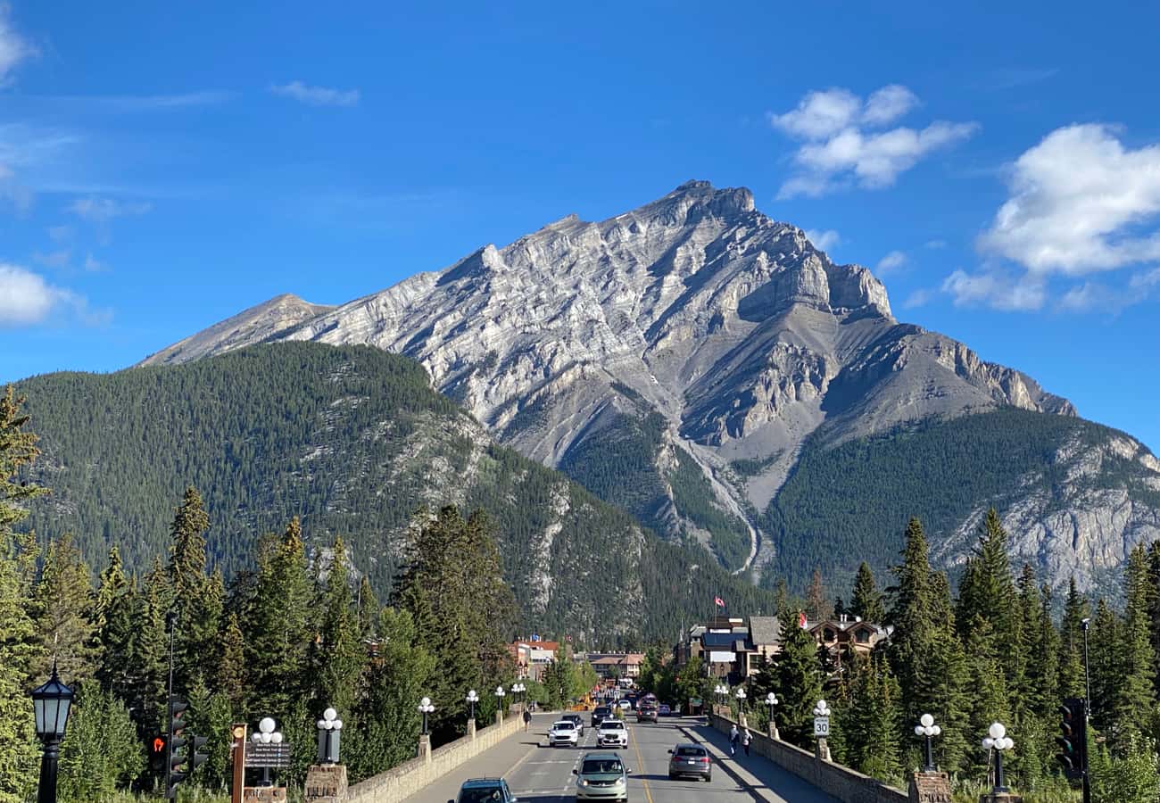 Banff Avenue bustling beneath the towering imposing rock face of Cascade Mountain