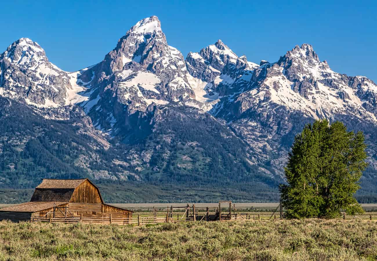 Historic wooden barn at Mormon Row framed against the towering Grand Teton range