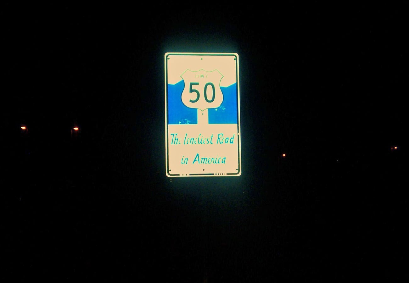 Loneliest Road in America sign at night along US Route 50 in Nevada