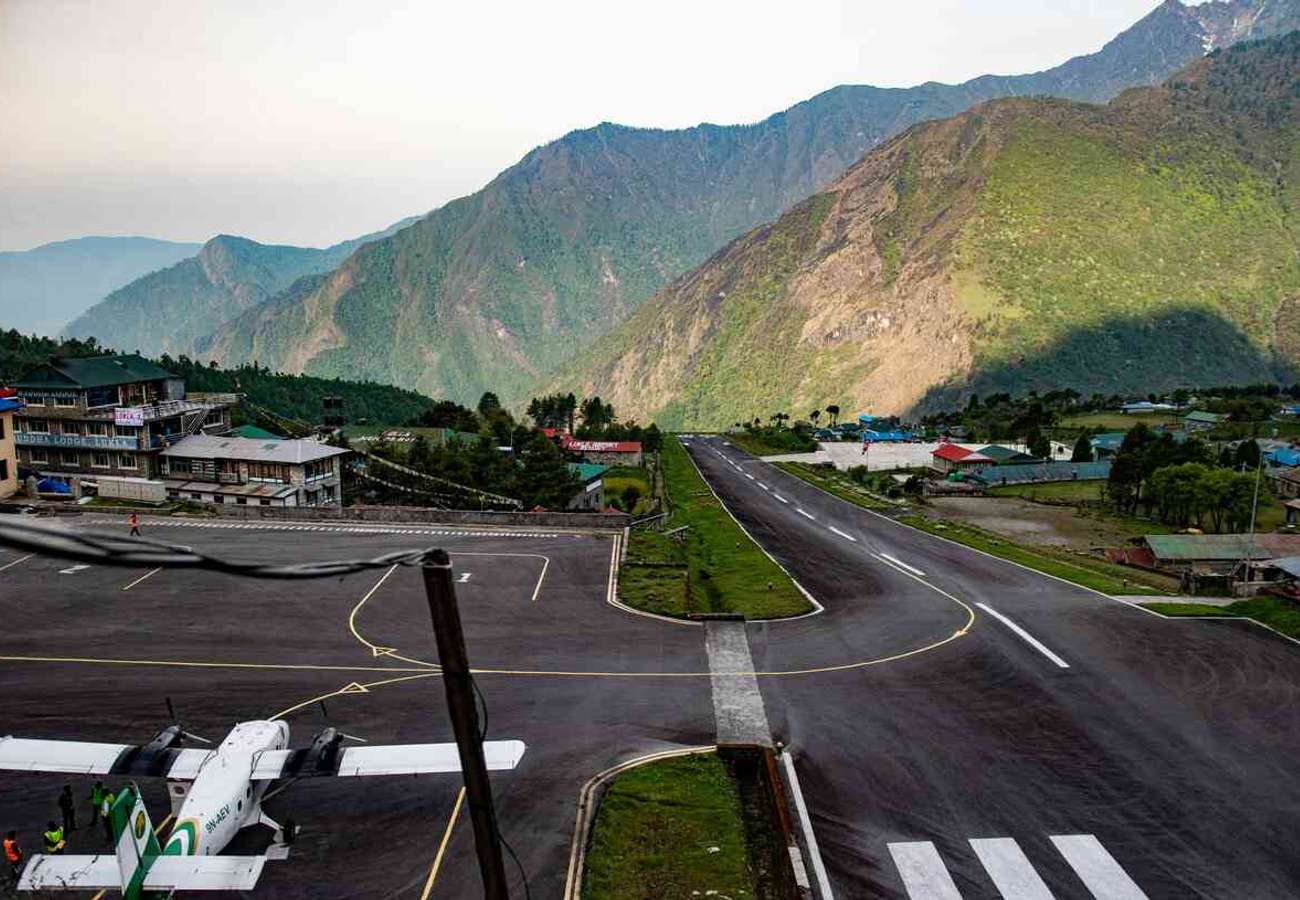 A small Twin Otter aircraft landing on the short, sloping runway of Tenzing-Hillary Airport in Lukla, Nepal